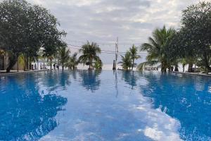 a large swimming pool with blue water and trees at Maruti Beach Villas in Nusa Penida
