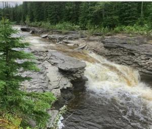 a river with water rushing over the rocks at Hidden Creek Cabin in Beaverlodge +31 photos
