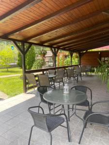 a patio with tables and chairs under a wooden roof at Gama House & Garden with restaurant in Vişeu de Sus +58 photos