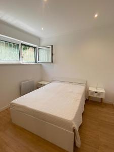 a white bedroom with a bed and two windows at Maresia BIKE ROOMS in São Félix da Marinha