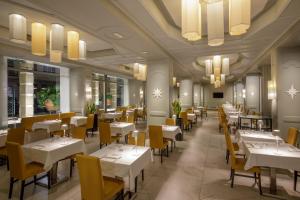 ein Restaurant mit weißen Tischen und gelben Stühlen in der Unterkunft Grand Hotel Fleming by OMNIA hotels in Rom