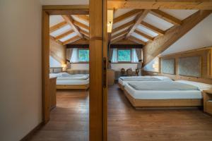 two beds in a room with wooden ceilings at Hotel Crozzon in Madonna di Campiglio +94 photos