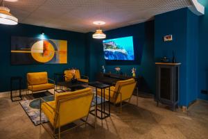 ein Zimmer mit blauen Wänden, gelben Stühlen und einem Fernseher in der Unterkunft Aria Life Hotel in Limone sul Garda