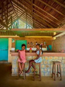 two young girls sitting at a counter in a bar at Bungalow Bleu Villa Luna Nosy Be in Nosy Be