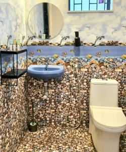 a bathroom with a toilet and a sink with a mosaic wall at Daffodil in Anjuna