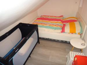 ハーネンクレー・ボックスヴィーゼにあるFewo Andresen Hahnenkleeの二段ベッドとベビーベッドが備わる小さな客室です。