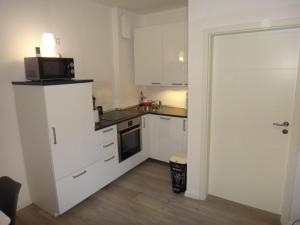 a small kitchen with white cabinets and a microwave at Fewo Andresen Hahnenklee in Hahnenklee-Bockswiese
