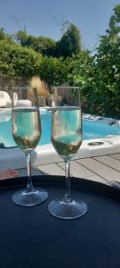 two wine glasses sitting on a table near a swimming pool at Sotto il fico in Agnino