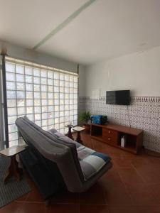a living room with a couch and a television at Maresia BIKE ROOMS in São Félix da Marinha
