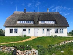 a white house with a thatched roof on a field at An der See in Dranske