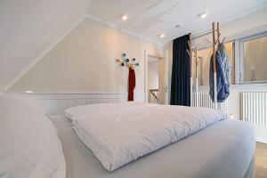 a white bedroom with a large white bed at An der See in Dranske
