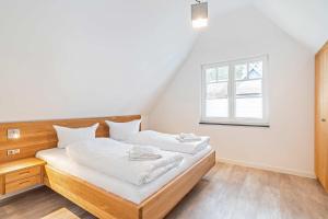 a bedroom with a bed with white sheets and a window at Ferienhaus Baltic Huus in Zirchow