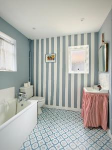a bathroom with a tub and a toilet and a sink at The Cottage at Cobbolds Mill in Monks Eleigh +10 photos