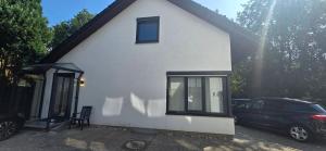 a white house with a car parked in front of it at White Coast Villa in Grömitz