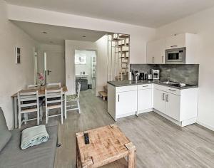 a kitchen and living room with white cabinets and a table at Bugoase in Dranske