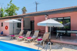 a group of chairs and umbrellas next to a pool at Villa Poppy by Villa Plus in Polis Chrysochous