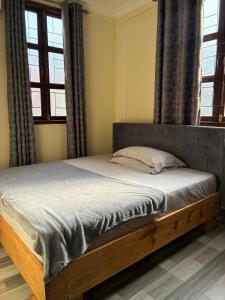a bed in a bedroom with two windows at Hakuna matata Apartments in Zanzibar City +6 photos