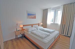 a bedroom with a bed and a table and a window at Am Ufer Top 13 in Dranske