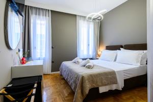 a bedroom with a bed with white sheets and windows at Swan Paradise Nafplio in Nafplio