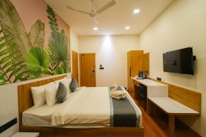 a bedroom with a bed and a desk and a television at MGM Vailankanni in Velankanni