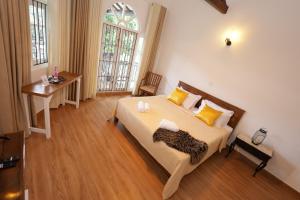 a bedroom with a bed and a table and a window at Mino Villa Kandy in Kandy