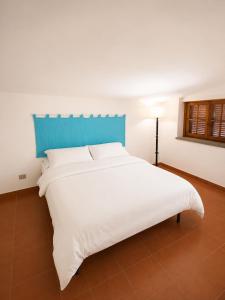 a white bed with a blue headboard in a room at Perla Marina Tropea in Parghelia