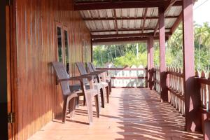 a row of chairs sitting on a wooden porch at Ghaniya Homestay in Bonto