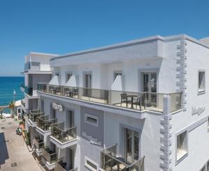 an apartment building with balconies and the ocean in the background at San Marine Beach Hotel, Heart of Chersonissos, Steps from the Sea in Hersonissos