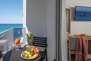 a table with a bowl of fruit on a balcony at San Marine Beach Hotel, Heart of Chersonissos, Steps from the Sea in Hersonissos