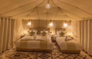 a bedroom with two beds in a tent at Royal Erg Chebbi Luxury Camp in Adrouine