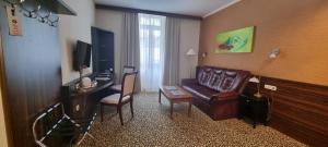 a living room with a couch and a desk and a television at Park Hotel in Hévíz