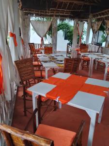 a dining room with white tables and chairs at Al Mar Bed and Breakfast in Watamu