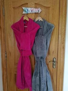 three dresses are hanging on a wooden door at Oceanview Cosy Cabin in Drumaville