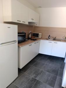 a kitchen with white cabinets and a sink and a refrigerator at Studio Boulazac proche Palio in Boulazac