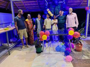 a group of people standing around a table with balloons at Misty field view Homestay in Ponnampet +21 photos