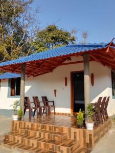 a house with a deck with chairs and a blue roof at Misty field view Homestay in Ponnampet