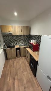 a kitchen with a white refrigerator and wooden floors at Victor Hugo's Le Central in Saint-Junien