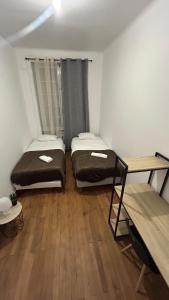 two beds in a room with a wooden floor at Victor Hugo's Le Central in Saint-Junien