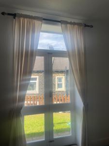 a window with white curtains in a room at Jagger Green Retreat in Greetland