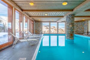 - une piscine avec des chaises dans une maison avec des montagnes dans l'établissement Lagrange Vacances Aspen, à La Plagne