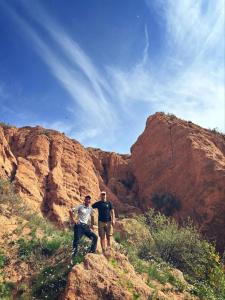 two people standing on the side of a mountain at Asman Tör Yurt Camp in Tong