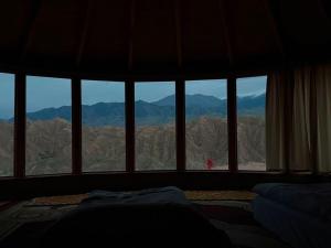a bedroom with a view of mountains from a window at Asman Tör Yurt Camp in Tong