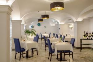 a dining room with white tables and blue chairs at Hotel Shangri-La Roma by OMNIA hotels in Rome