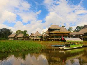 ein kleines Boot im Wasser vor einigen Gebäuden in der Unterkunft Libertad Jungle Lodge in Yucuruche