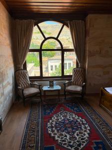 a living room with two chairs and a large window at Akuzun Stone Hotel in Ürgüp