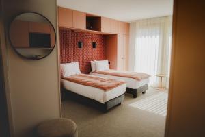 a hotel room with two beds and a mirror at Apparté Plus in Brive-la-Gaillarde