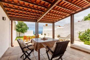 an outdoor patio with a wooden table and chairs at Casa Teide, disfruta de el atardecer en tu gran terraza privada in Icod de los Vinos