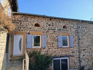 a brick building with windows and blue curtains on it at Chez steph studio in Saint-Germain-Nuelles