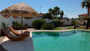 a swimming pool with two chairs and an umbrella at Villa Anna in Quartu SantʼElena