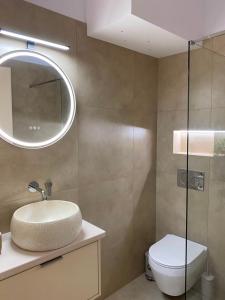 a bathroom with a sink and a toilet and a mirror at Folia City Center with Parking in Chalkida